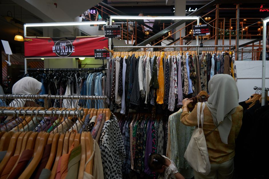 Shoppers browse a variety of clothes in a bustling indoor clothing store.